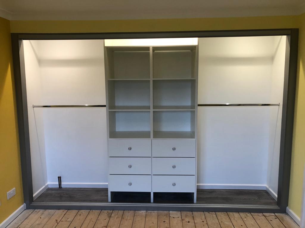 Grey framed fitted wardrobe interior with white drawers and shelving in Pontypridd