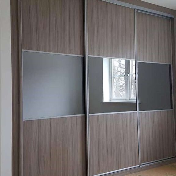 Wood effect solid panel sliding wardrobe doors with grey and mirror inserts in a Nelson bedroom