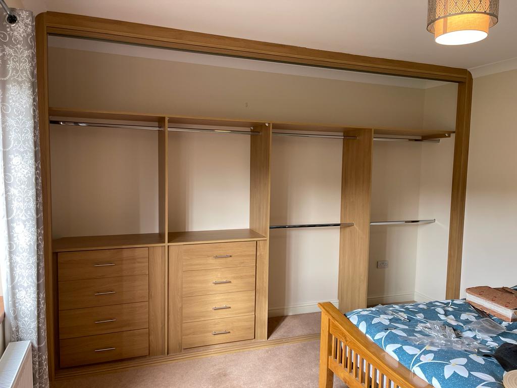 Oak fitted wardrobe interior with drawers and hanging rails in a Penarth bedroom