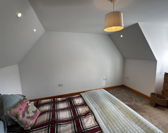 Empty sloping loft wall in Cowbridge before grey tinted glass sliding wardrobe doors were fitted
