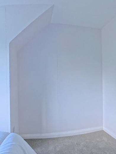 Empty angled bedroom alcove with bare walls before fitted wardrobes were installed