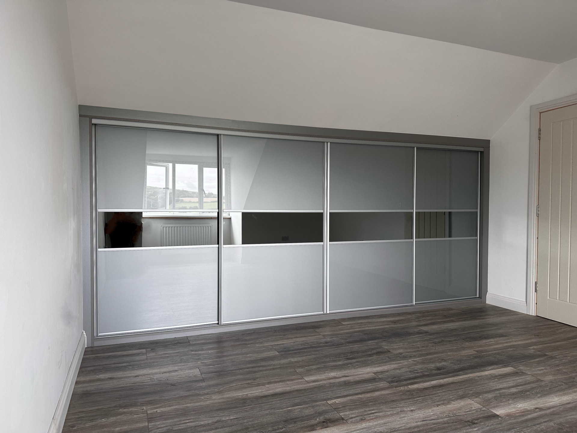 Metal grey glass sliding wardrobe doors with a central tinted mirror panel in a Merthyr Tydfil bedroom