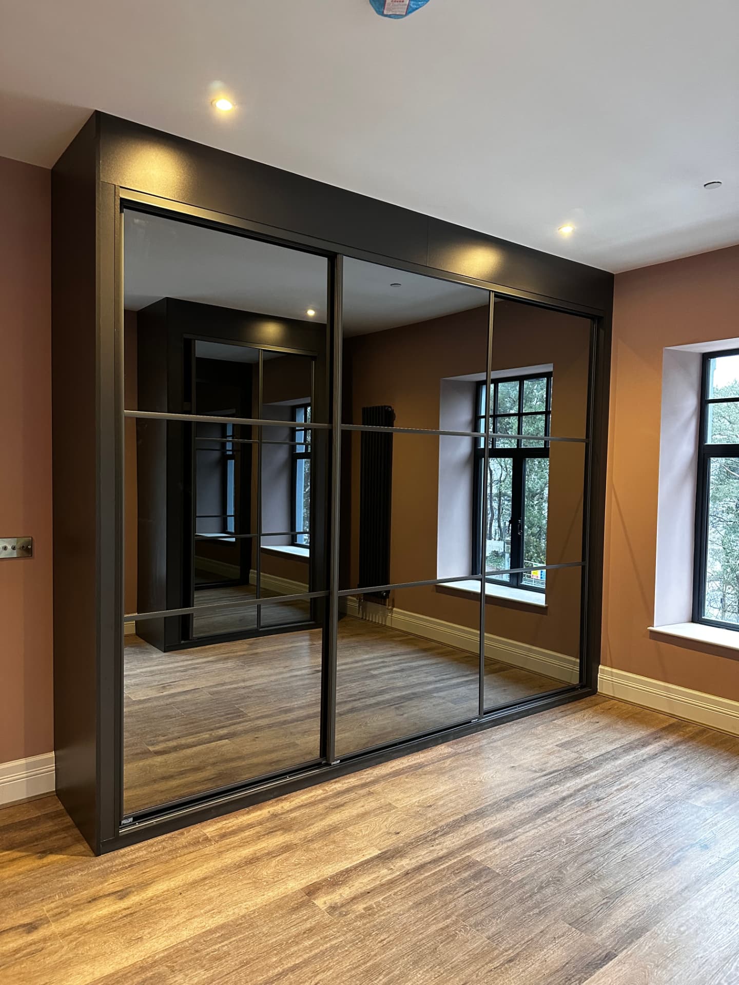 Frameless mirror sliding wardrobe doors in a bright Treforest bedroom