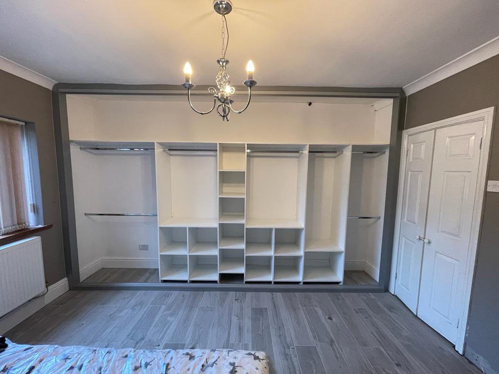 Grey framed fitted wardrobe interior with a full run of white shelves and hanging rails in Newport