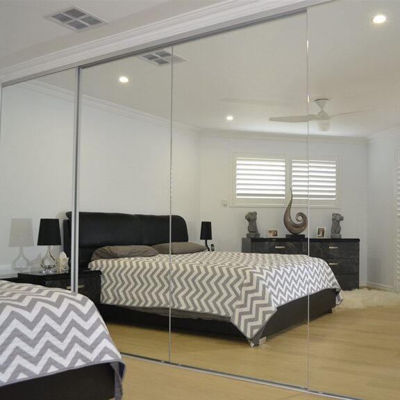 Mirror sliding doors mixed with pale panels in a Bridgend bedroom