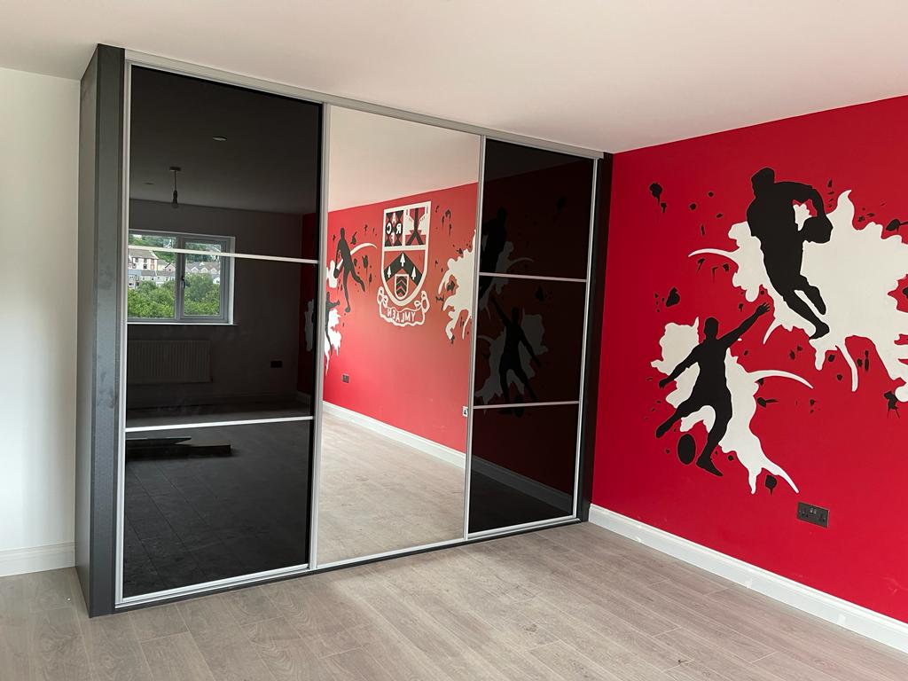 Black glass sliding wardrobe doors in a rugby-themed children’s bedroom in Cardiff Bay
