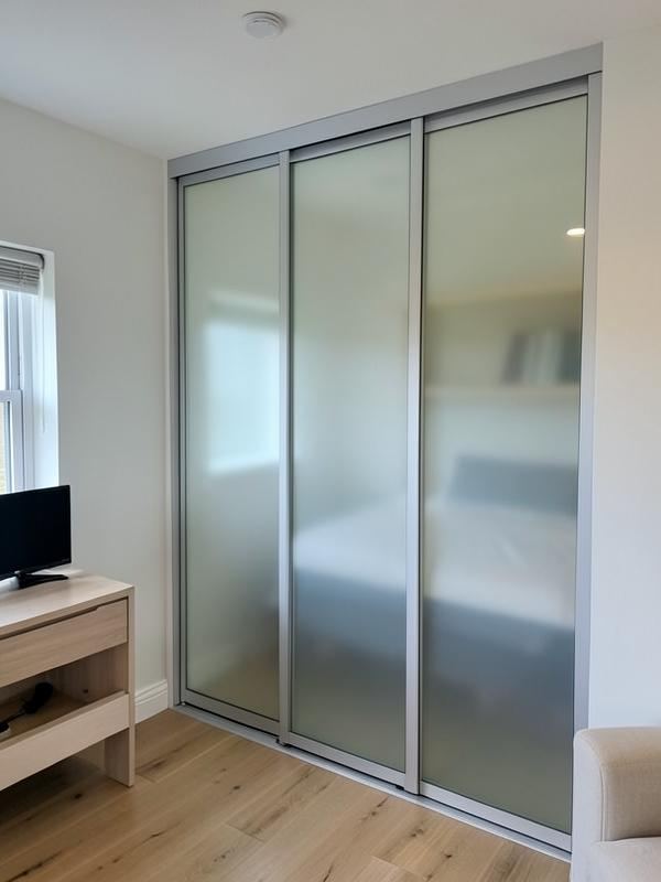 Safety-backed glass sliding wardrobe doors fitted in a family bedroom in South Wales